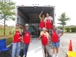 Friends of the Library standing in and in front of the back of an open box truck